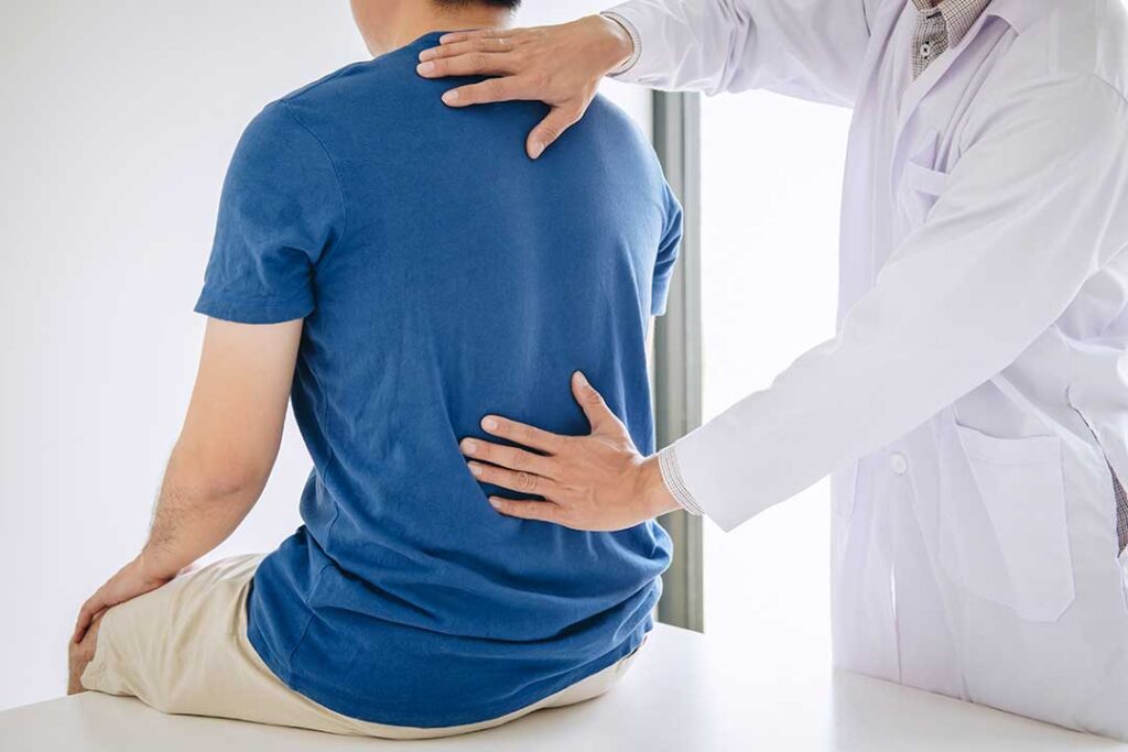 Person practicing balance near a wall while a clinician observes posture and foot placement.